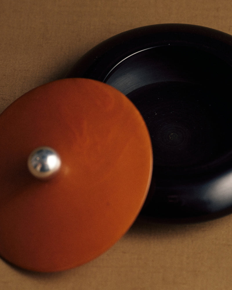 Two-tone German Bakelite container, 1920s — sterling silver ball handle, angled view with lid off.