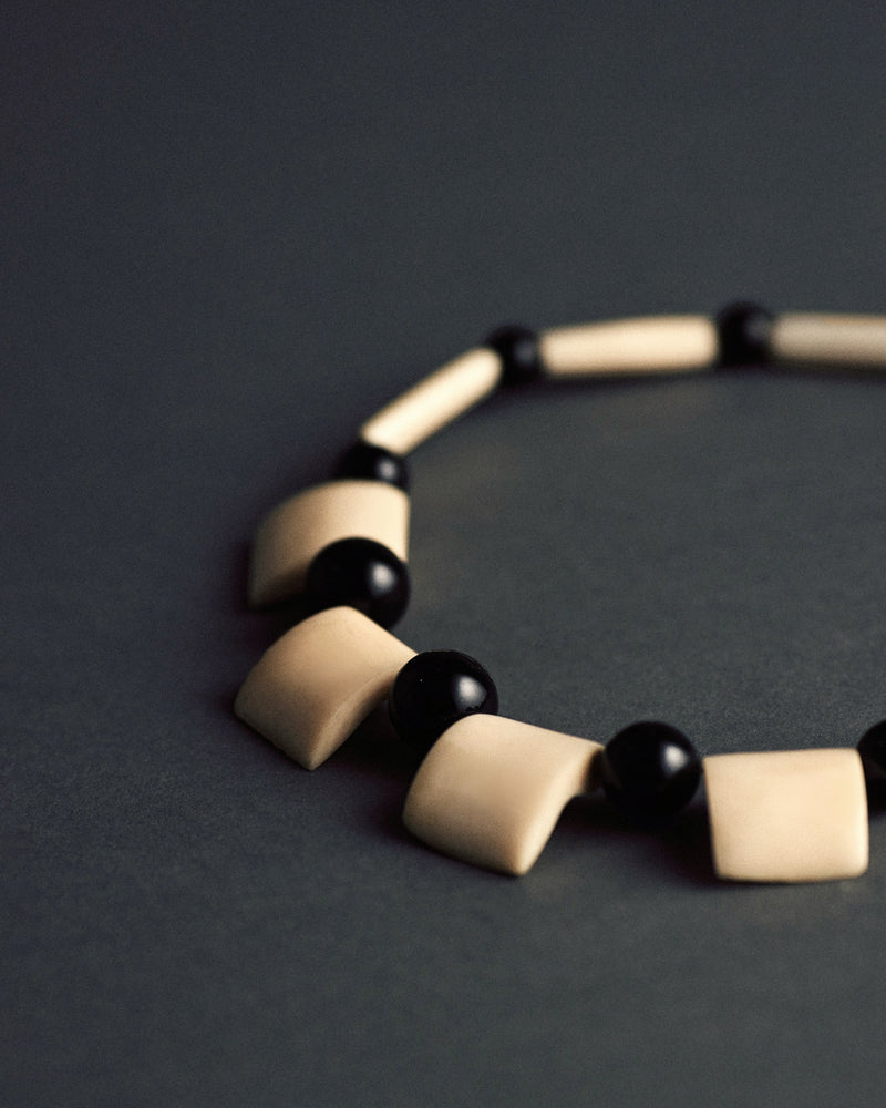 Carved bone and bead necklace — close-up of bone elements and black beads.